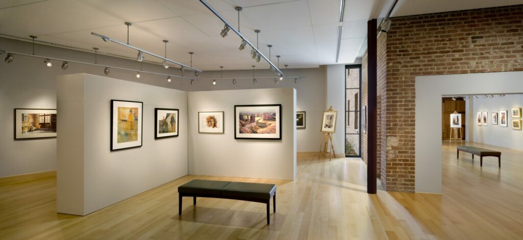 Several art pieces are displayed on the walls of an empty gallery