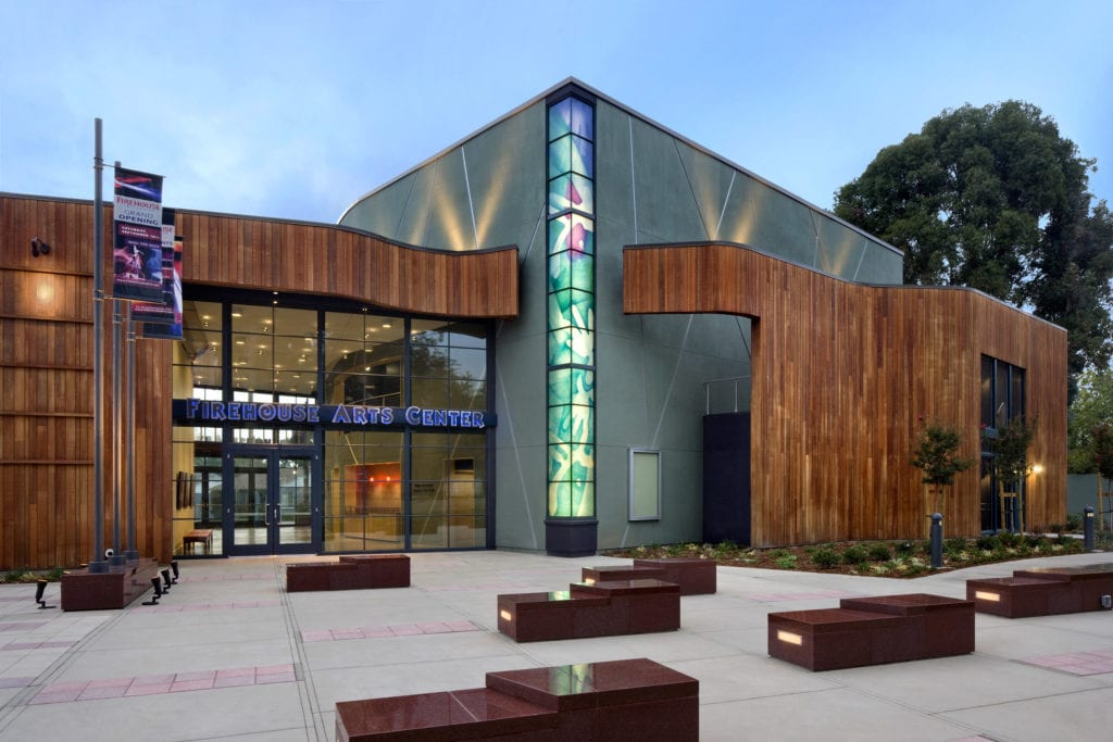 Modern event center with glass windows and seating area outside the Firehouse Arts Center in Pleasanton.