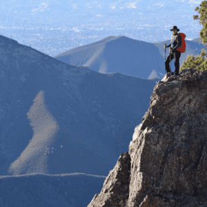 A woman peers at the valleys below from a high ridge